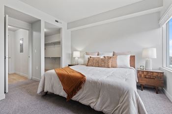 A bedroom with a large bed and a wooden end table.